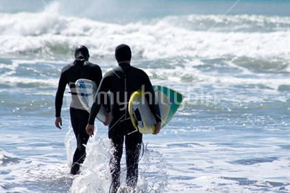 Two surfers heading out