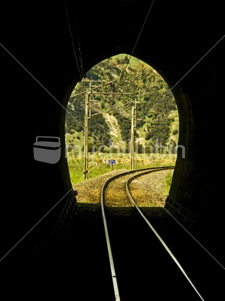 Light at the end of the tunnel; curved railway lines entering or leaving a tunnel on the main trunk line in the Central North Island, New Zealand.