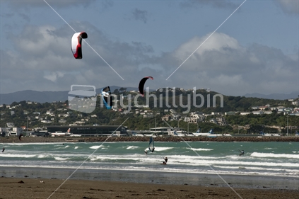 Kitesurfers and windsurfers at Lyall Bay beach, Wellington Airport in the background