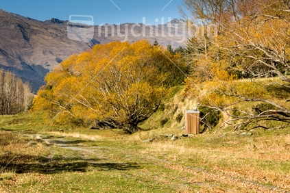 A rusting shed surunded by willow trees on the bank of the Matukituki River near Wanaka