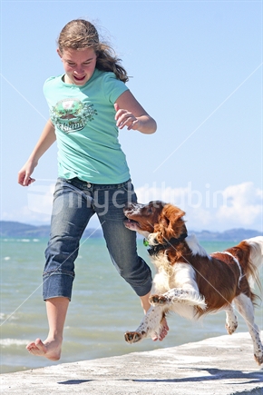 Teenage girl and Welsh Springer Spaniel dog running at the beach