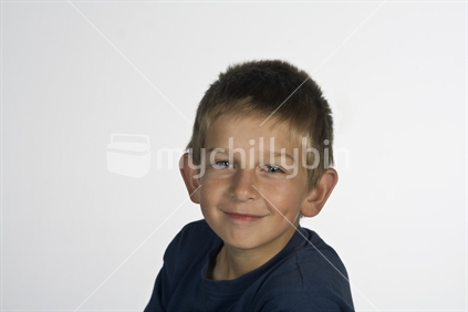 Male child in studio with grey background, head and shoulders shot