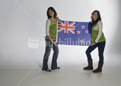 Female identical twins in studio holding a New Zealand flag