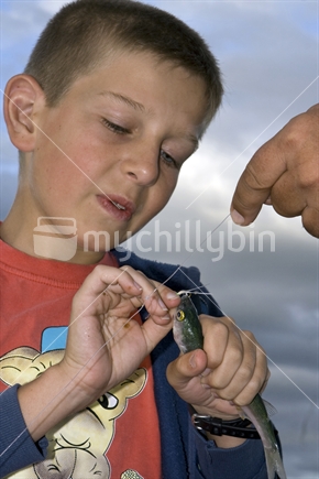 Child taking a fish off the hook, New Zealand