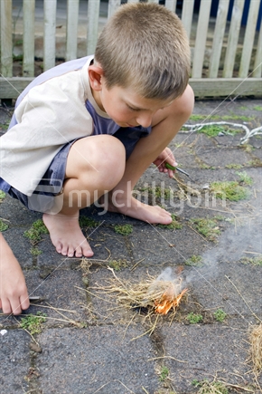 Boy lighting a fire with a flint
 