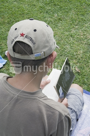 Male teenager reading at a park