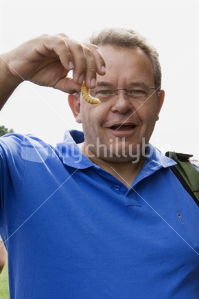 Man holding a Huhu grub at the wild food festival