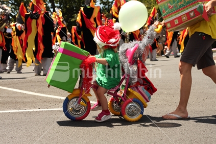 Girl riding a tricycle at a santa parade.