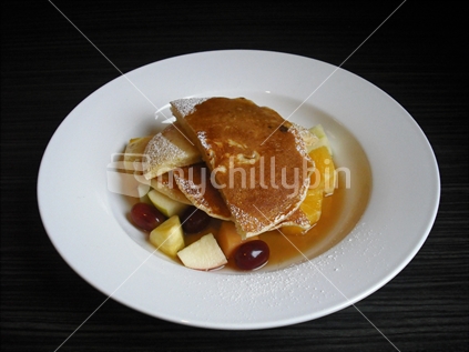 Pancakes with mixed New Zealand fruits and maple syrup.