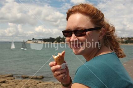 woman sitting at Takapuna beach eating icecream
