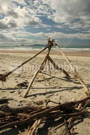 Driftwood pile and structure, at Waipu Cove beach, New Zealand
