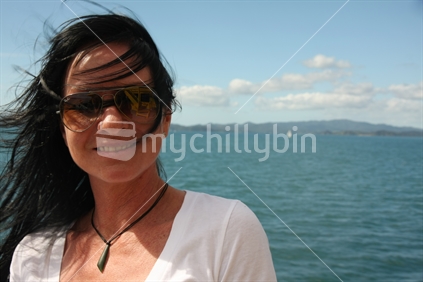 Woman enjoying the New Zealand summer sun at the beach. 
