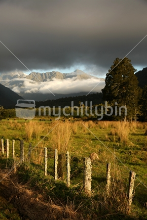 West Coast mountains, farm and fence; before the storm, South Island, New Zealand