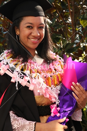 Female graduate with a bouquet in her hand and a chocolate necklace
