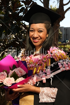 female graduate with a bouquet in her hand and wearing a traditional Tongan outfit.