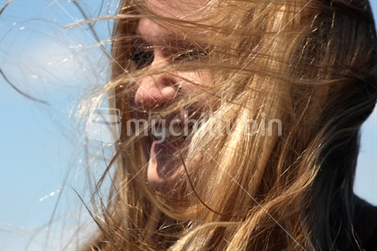 Woman laughing outdoors in the sun and wind (focus near hair)