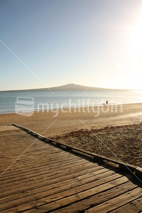 Couple walking along Narrow Neck beach on clear morning, North Shore, Auckland
