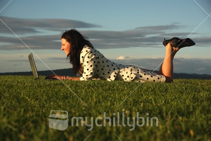 Woman on the grass, with a laptop.
