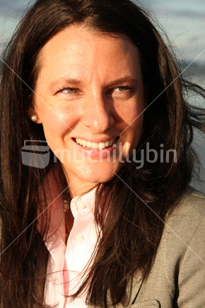 Woman smiling in late afternoon autumn light in Auckland. 
