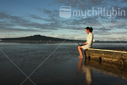 Woman sitting on a raft with Rangitoto Island in the background, Devonport, Auckland