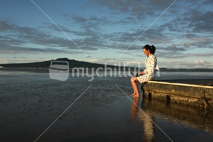 Self employed woman working with a laptop on a raft (with Rangitoto Island in the background)