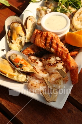 Seafood platter with mussels, prawn skewers, and salmon.
