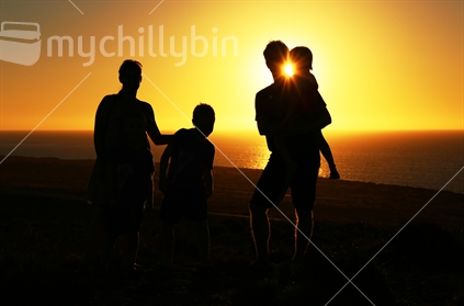 happy family of five silhouetted by setting sun