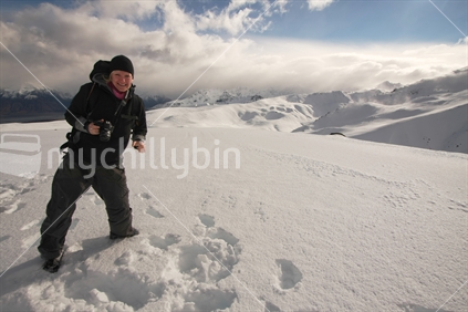Tourist photographer on top of a snowcapped mountain near Aoraki Mt Cook, Southern Alps, New Zealand