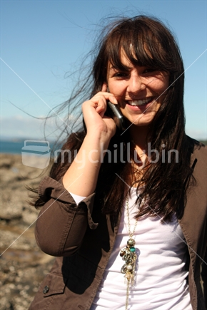 Young woman with a mobile phone at the beach