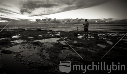Fisherman with fishing rod and chillybin, at Muriwai, Auckland.