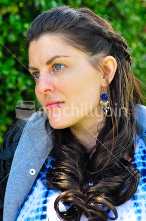Young Woman relaxing in the park, with day dreaming or wistful look. 