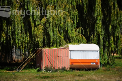 Retro caravan and striped orange awning parked in campground