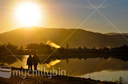 Couple walking along waters edge at dusk in Moueka