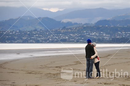 Couple hugging on beach on winters day 
