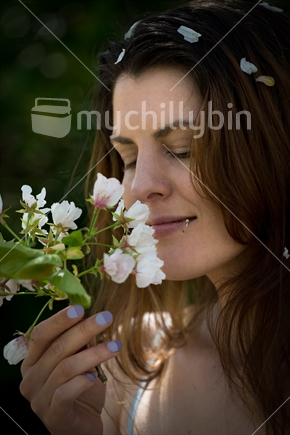 Young New Zealand woman smelling spring blossom flowers 