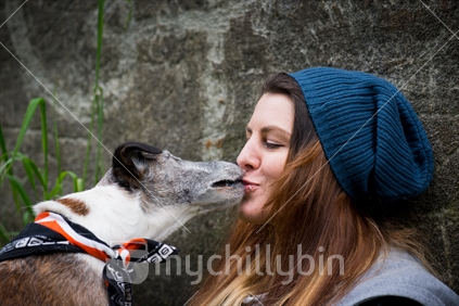 Young woman kissing a dog.