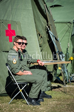 Two young RNZAF pilots sitting outside airforce medical first aid tent at training camp in Nelson