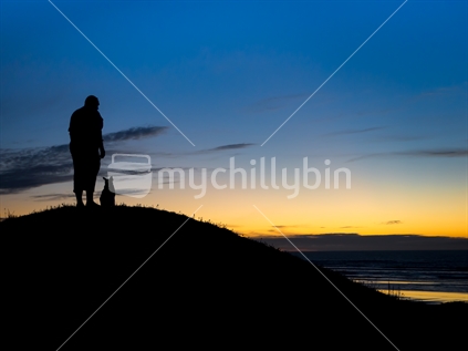 Silhouetted Man and dog watching the sunset at dusk from a farm on the West Coast on Christmas Day 2014