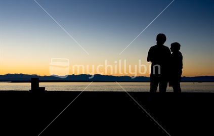 Adult and child on wharf enjoying sunset
