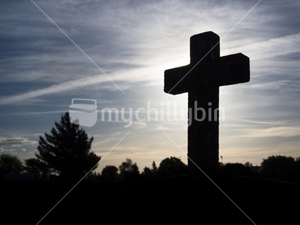 silhouetted cross headstone in cemetery in Marlborough