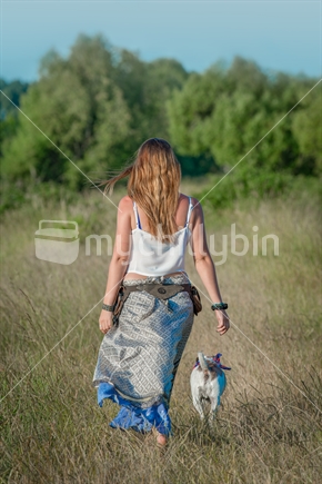 Young woman walking old dog through long grass