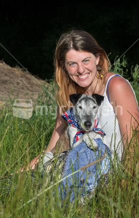 Young woman sitting in long grass with elderly fox terrier