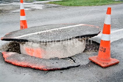 Earthquake damage to the road in Christchurch. Both the road has dropped and the manhole has been forced up, September 2010