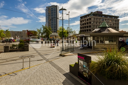 Spring (2014) in Cathedral Square, Christchurch. The Police kiosk in the foreground. Bereft of people the Square is very quiet on this Monday morning. In the far background is one of the few remaining tall buildings, still empty and boarded up. 