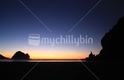 Sunset over Piha Beach, West Coast, North Island with Taitomo Island (Camel Rock) to the left and the tip of Lion Rock to the right.