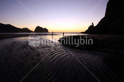 Sunset over Piha Beach, West Coast, North Island with Taitomo Island (Camel Rock) to the left and the tip of Lion Rock to the right.