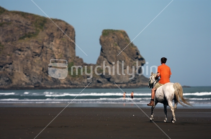 Man riding horse on Bethells Beach, West Coast, North Island