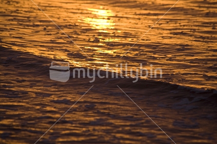 Sunset reflecting golden on waves at the shore