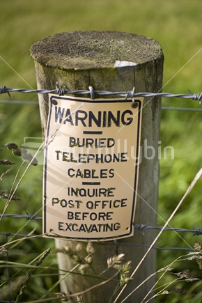 Telephone cable warning on a fence post