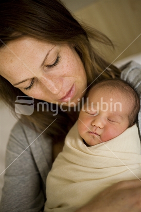 A mother holds her new born baby wrapped in swaddling